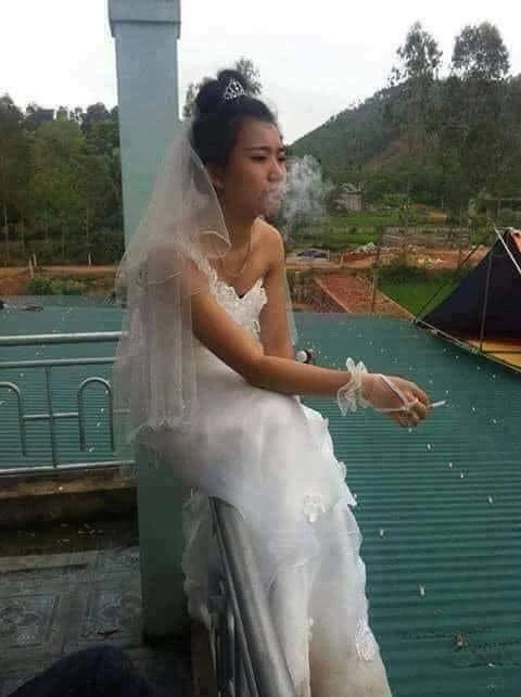 Cô dâu mặc váy cưới ngồi hút thuốc nhìn xa xăm