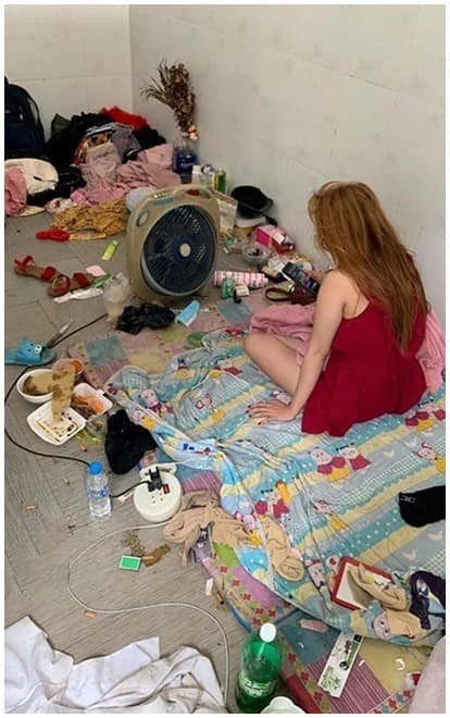 Hình ảnh cô gái ngồi giữa căn phòng bừa bộn đầy rác