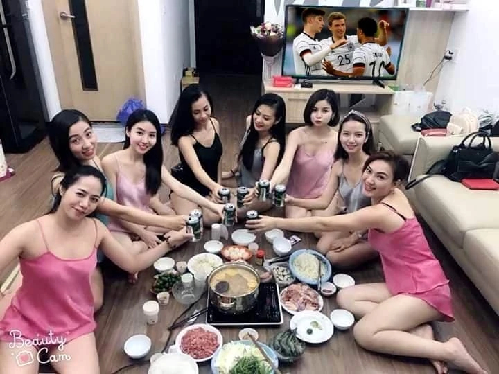 Một nhóm các cô gái mặc quần áo gợi cảm uống bia xem bóng đá